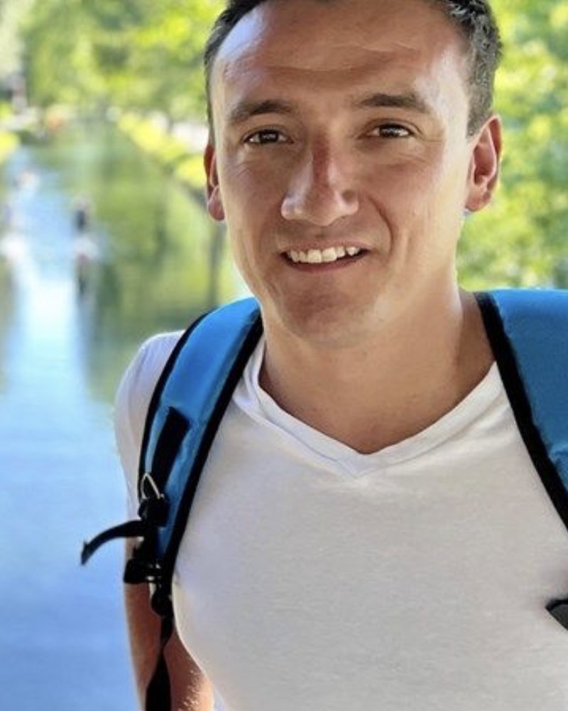 Benjamin Lowe outdoors by a canal, wearing a backpack